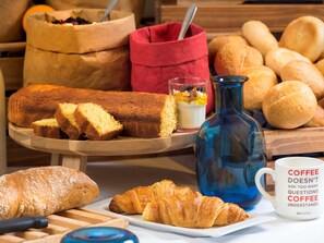 Variedad de productos horneados, incluyendo pan, un pastel y un croissant, sobre una tabla de madera.