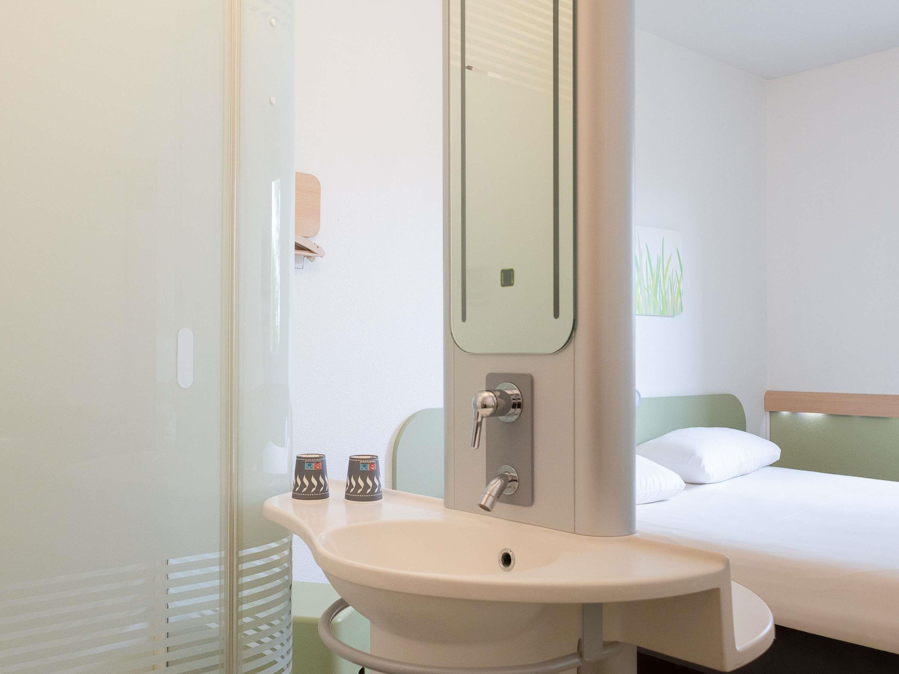 Une chambre d’hôtel avec un lit, un lavabo et un miroir.