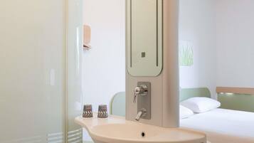 Une chambre d’hôtel avec un lit, un lavabo et un miroir.