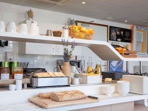 Ein Frühstücksbuffet mit Brot, Beilagen und einem Obstkorb.