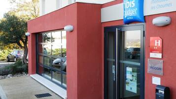 A modern building with a red facade, a glass entrance, and a sign for ibis budget hotels.