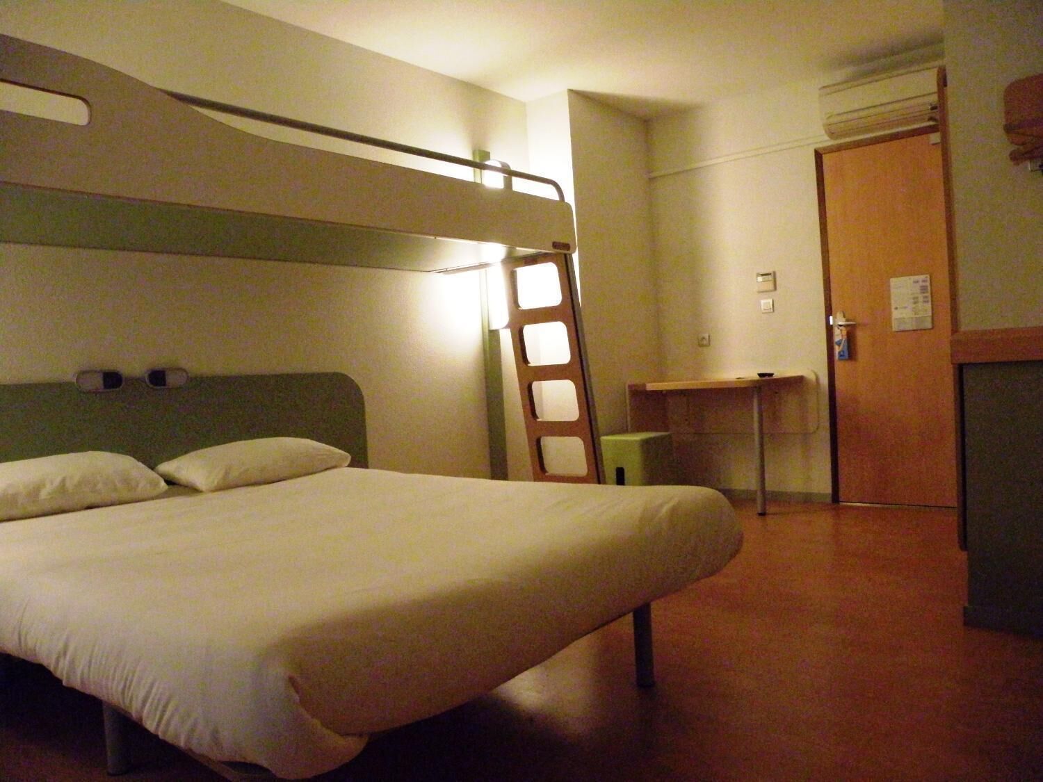 A single-bed room with a bunk bed, a desk, and a chair.