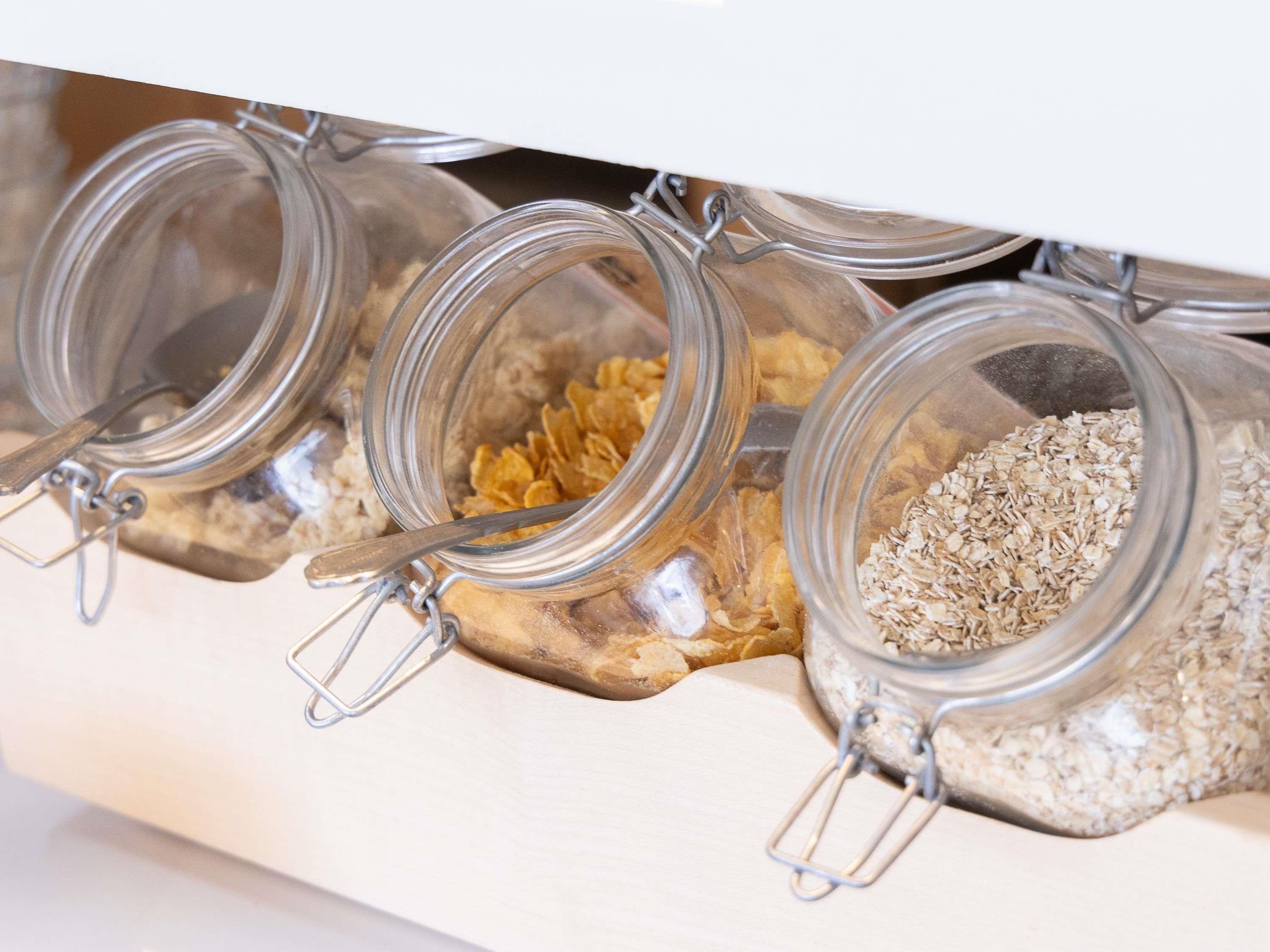 Three glass jars with metal clasps, containing different food items, placed on a shelf.