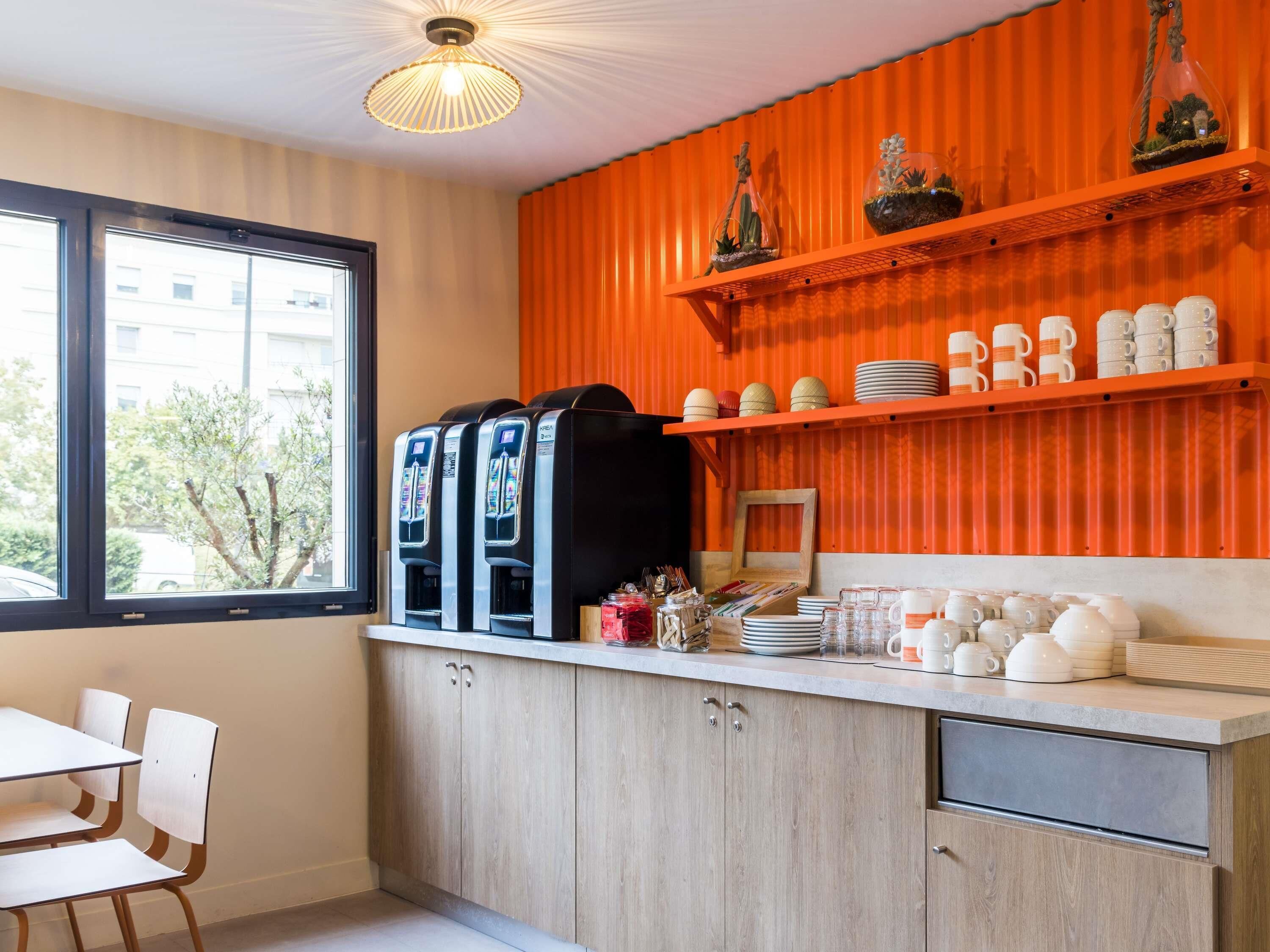 A modern kitchen with a window, a water dispenser, and shelves with dishes and decorative items.