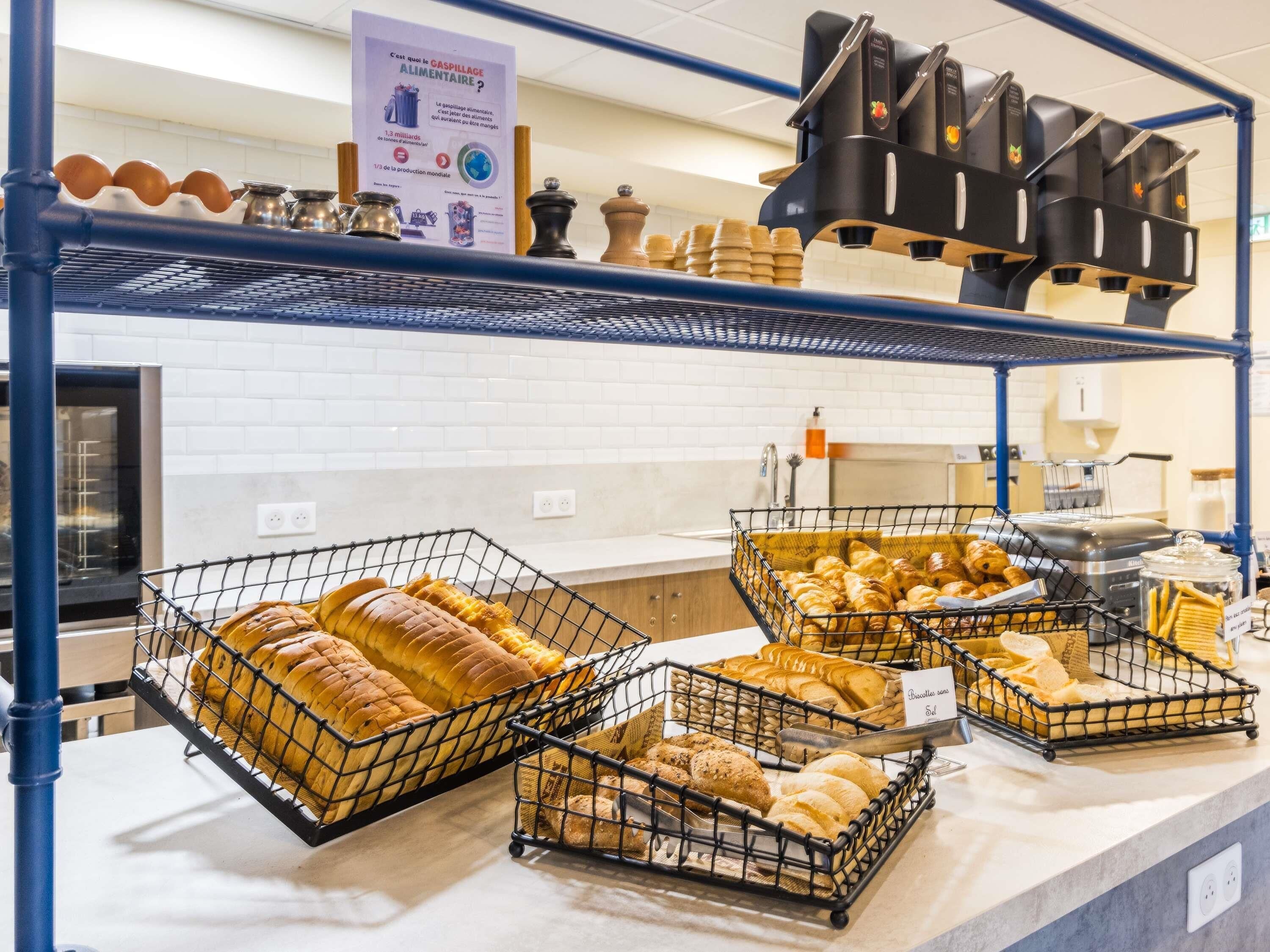 A bakery display with various breads and pastries, a coffee machine, and a sign about food production.