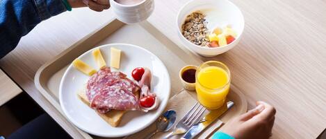 A breakfast tray with a plate of food, a cup of coffee, a bowl of cereal, and a glass of orange juice.