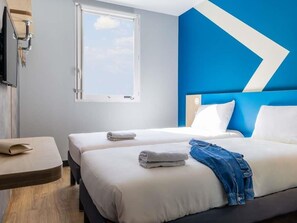 A hotel room with two beds, a window, a wall-mounted TV, and a desk. - ibis budget Chatillon Paris Ouest (Chatillon)