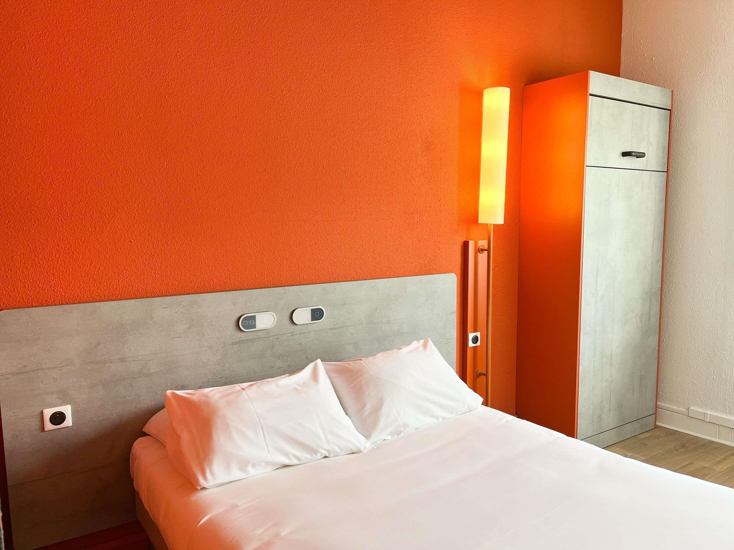 Ein Hotelzimmer mit einem Bett, einem Kleiderschrank und einer Wandleuchte.