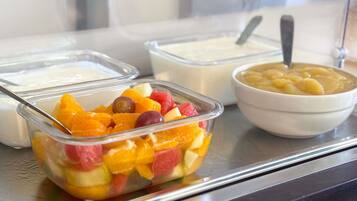 A buffet with various food items including a fruit salad, yogurt, and a bowl of soup.