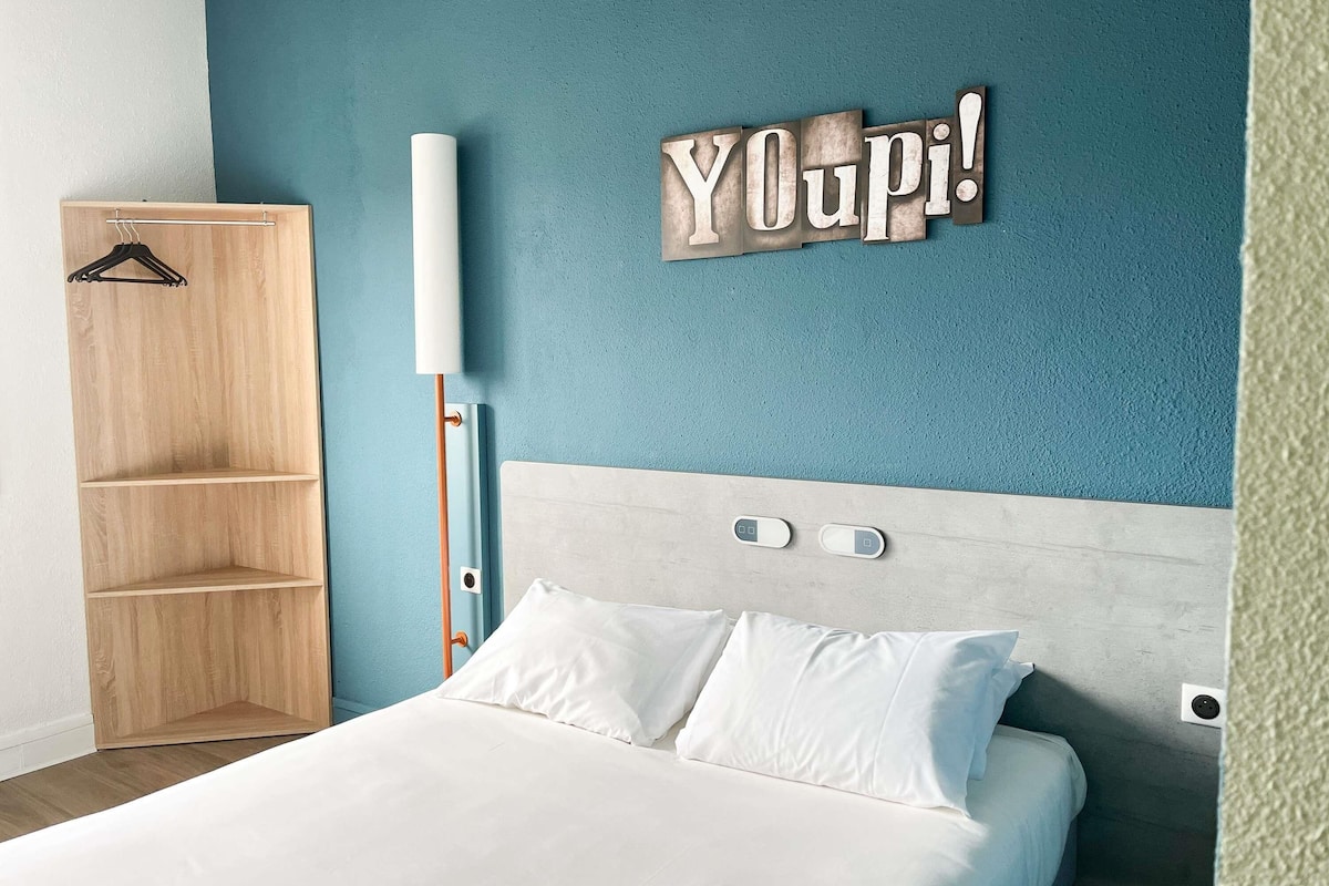 Un dormitorio con cama, un armario de madera y una lámpara fijada a la pared.