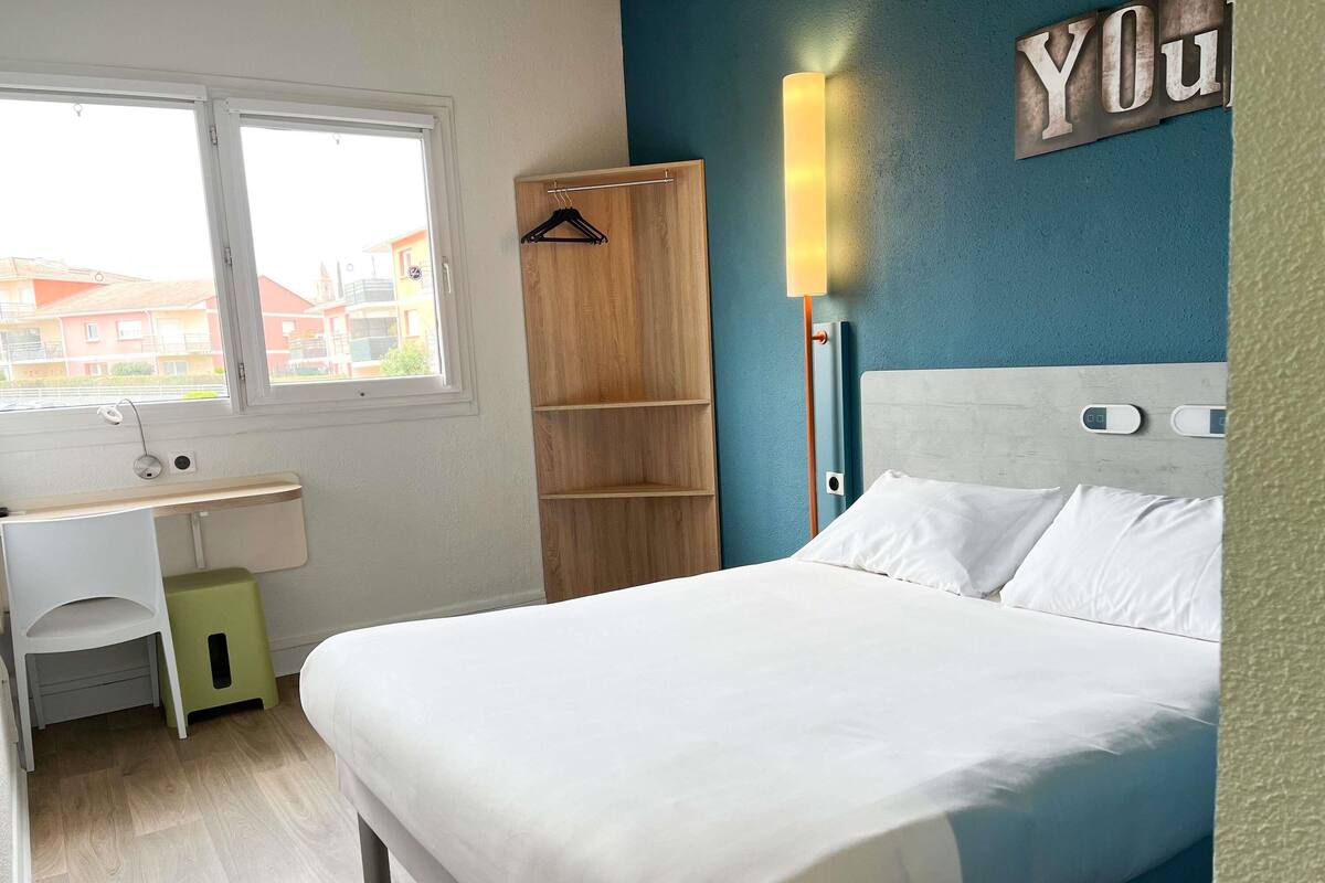 Un dormitorio con cama, escritorio y armario.