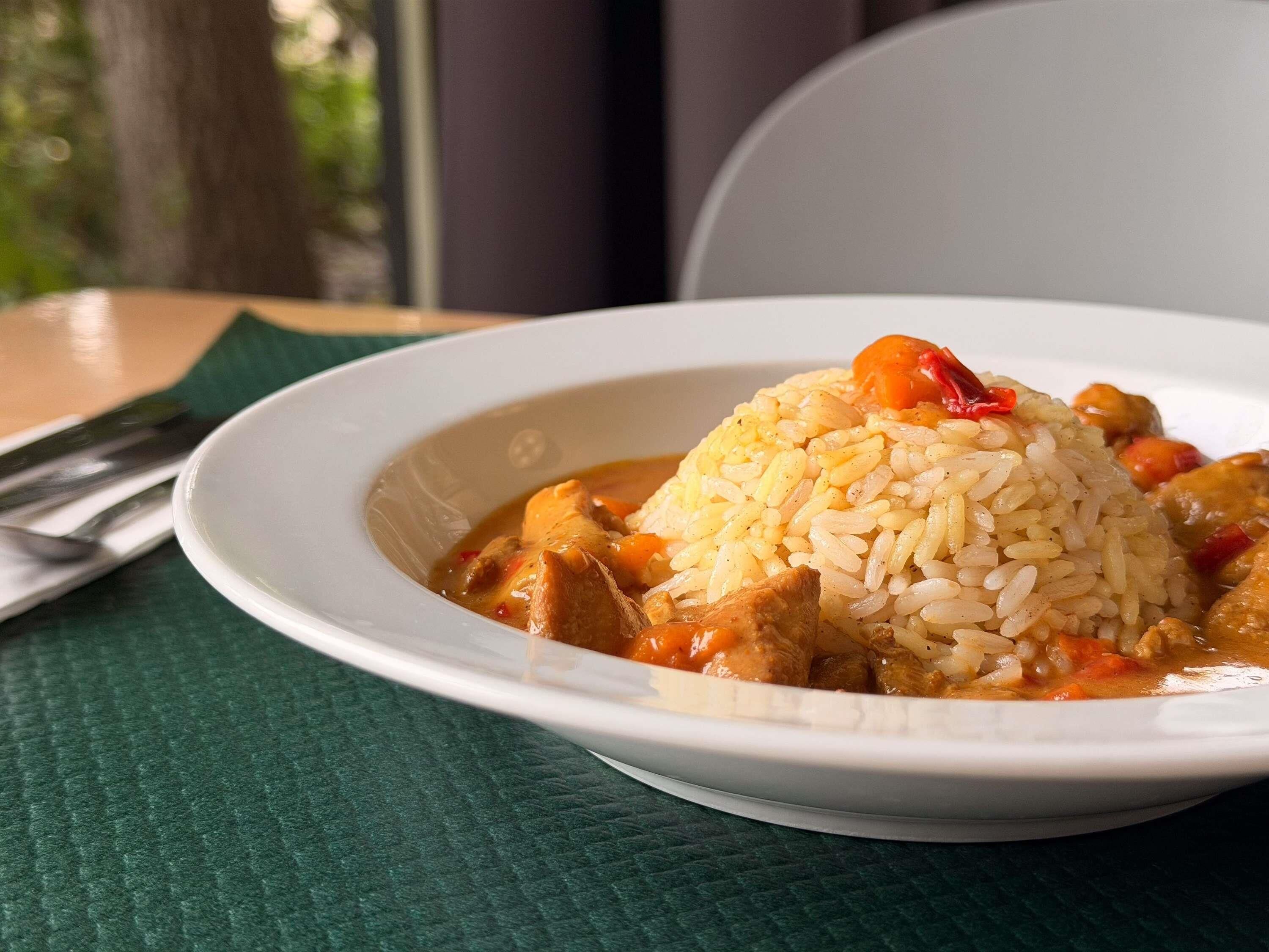A plate of rice and meat dish on a table with a green napkin and a fork.