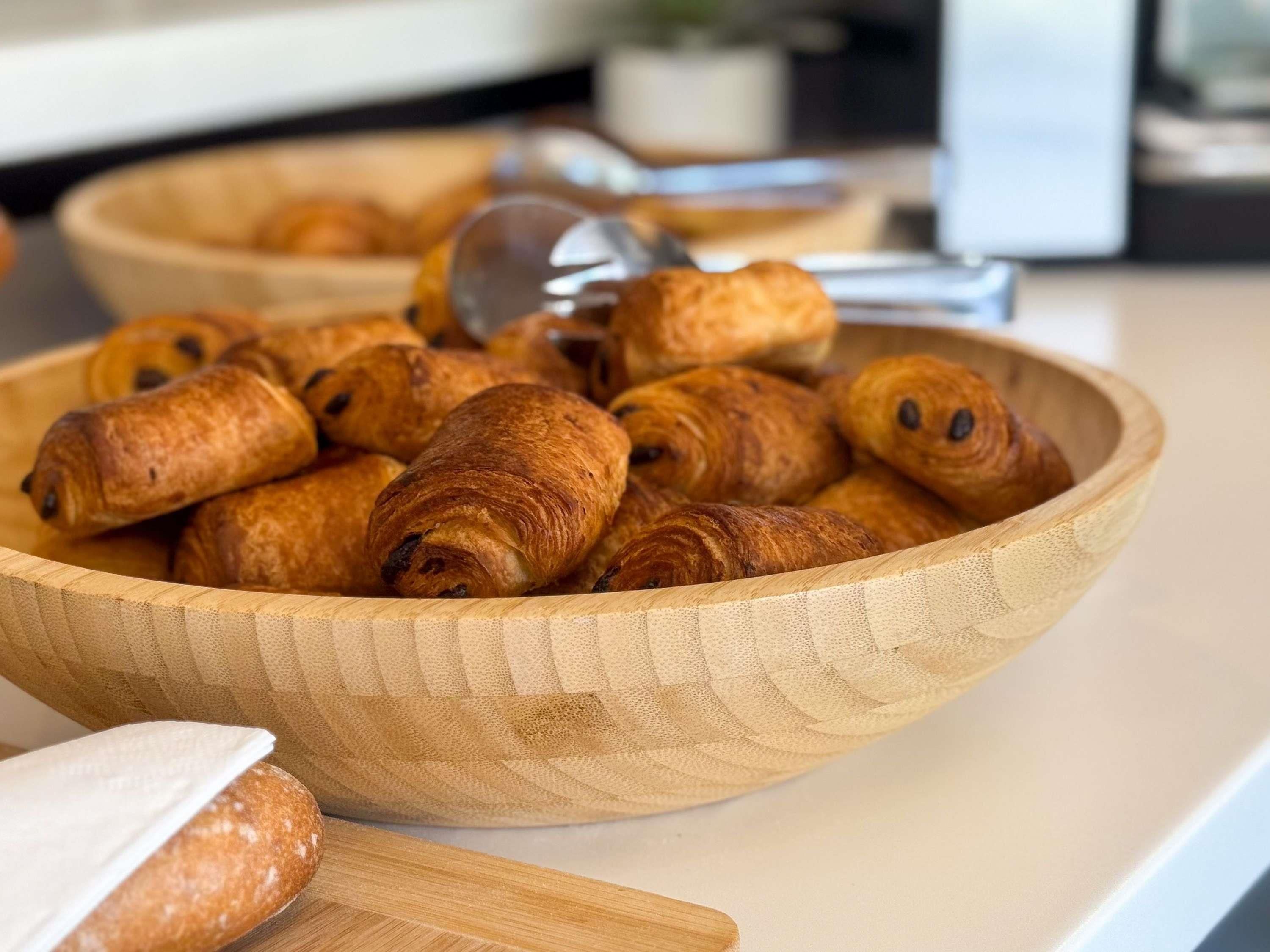 Un saladier en bois rempli de croissants, posé sur un plan de travail de cuisine.