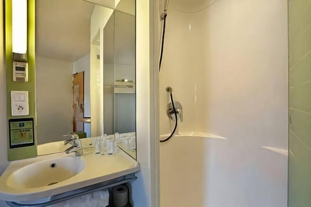 A bathroom with a sink, mirror, and shower.