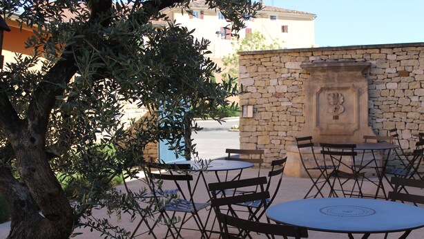 An outdoor seating area with stone walls and olive trees. - First Inn Hotel (Apt)