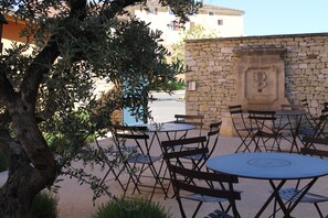 An outdoor seating area with stone walls and olive trees. - First Inn Hotel (Apt)