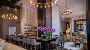 Un espace bar moderne doté d’un long comptoir, de tabourets de bar et d’un arrangement floral décoratif composé d’orchidées.