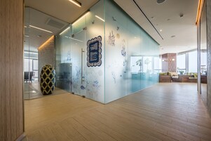 Un espacio de oficina moderno con paredes de vidrio, un jarrón decorativo y una zona de estar con vistas.