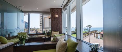 Una habitación de hotel moderna con un amplio ventanal que ofrece vistas a la playa y al océano.