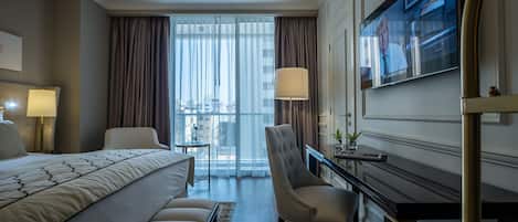 Una habitación de hotel moderna con una cama grande, un escritorio, una silla y un televisor.