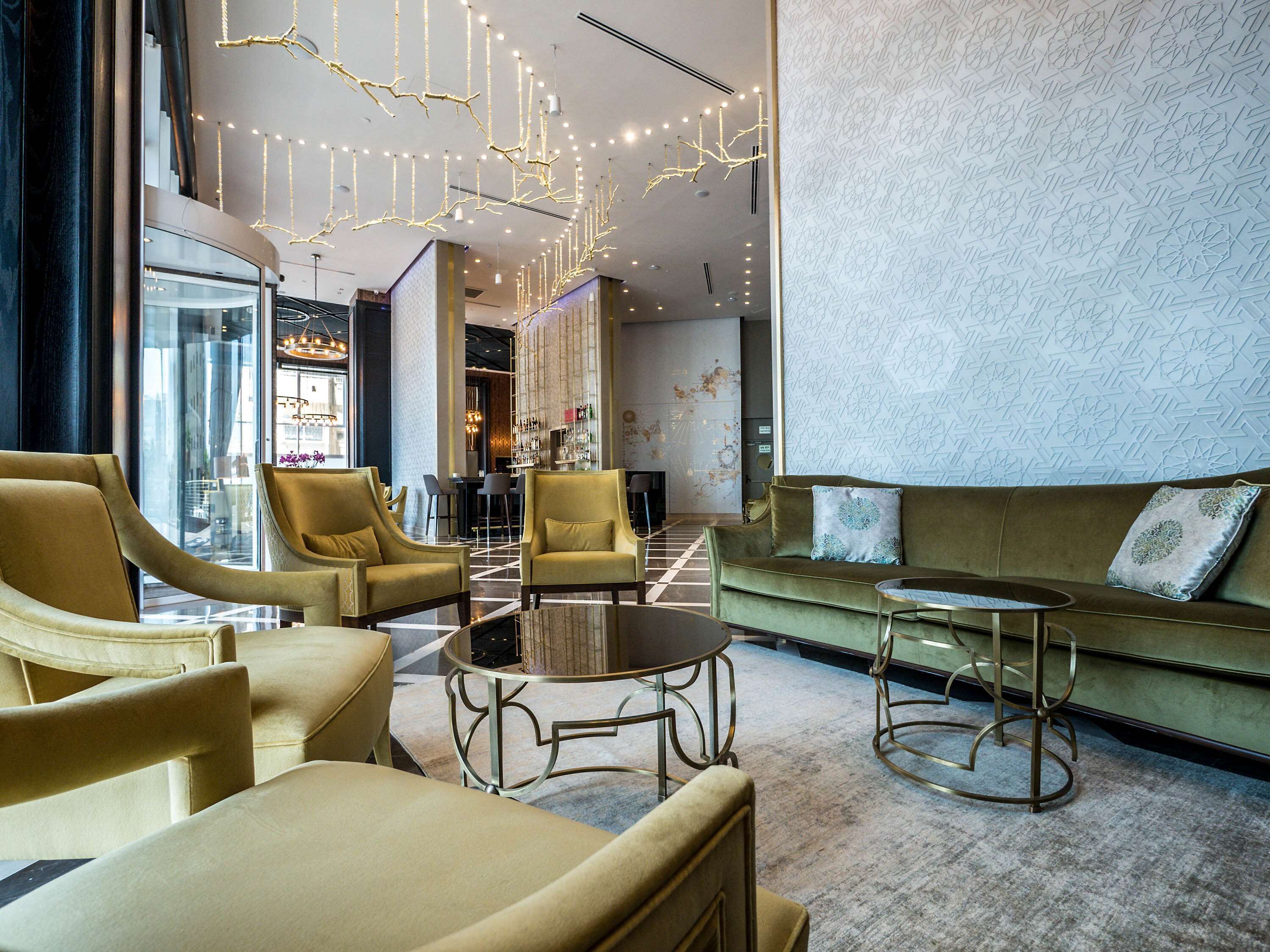Eine moderne Lobby mit Barbereich, Sitzgelegenheiten und dekorativer Beleuchtung.