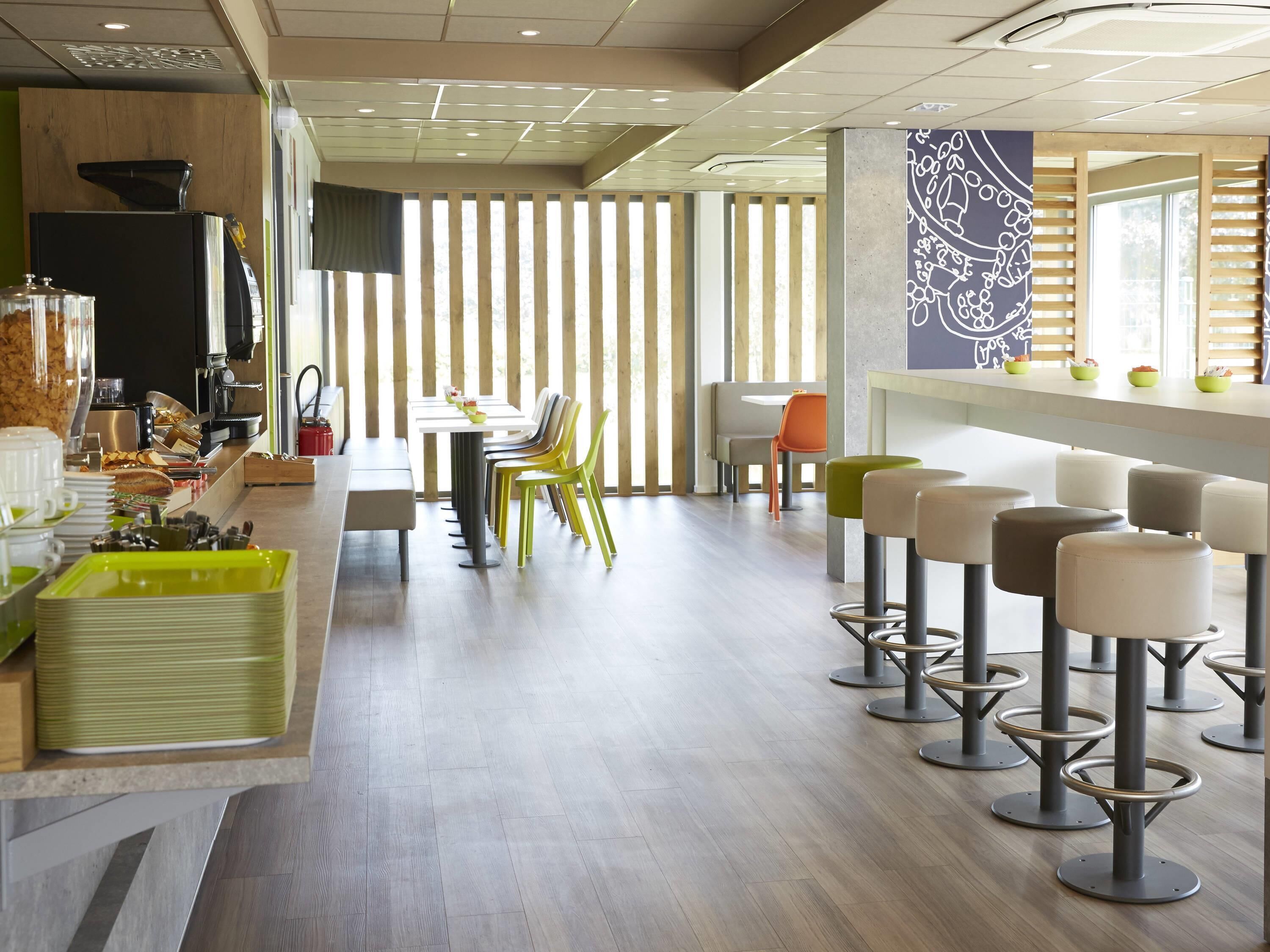 A modern cafe with a long counter, multiple chairs, and stools.