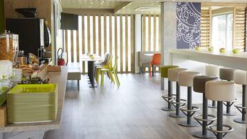 Een modern café met een lange toonbank, meerdere stoelen en krukken.