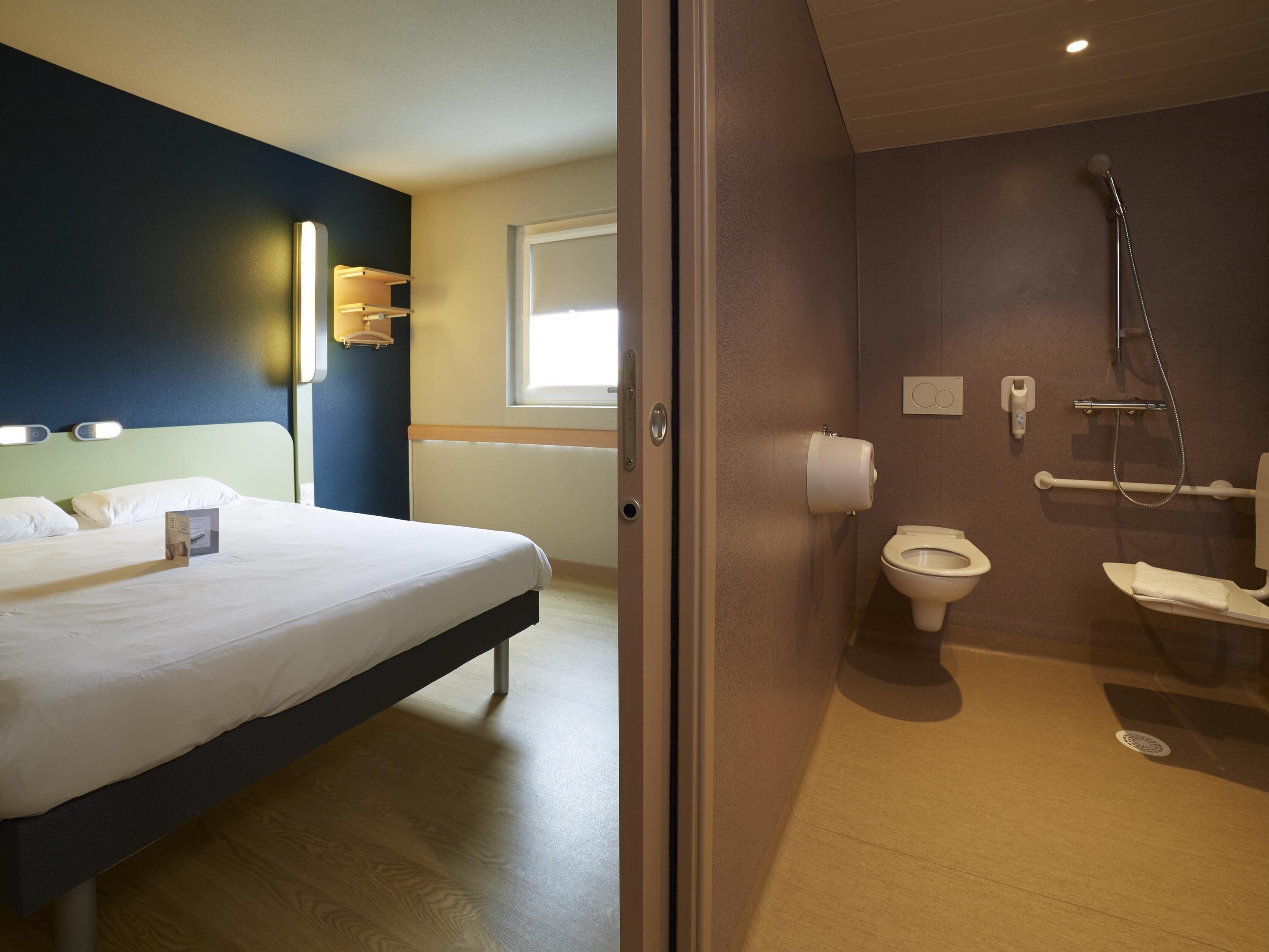 Ein Hotelzimmer mit Bett, Bad mit Toilette, Dusche und Fenster.
