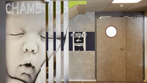 A hotel lobby with a large poster, a wooden door, and a sign on the wall. - ibis budget Chalon Sur Saone Nord (Chalon-sur-Saone)
