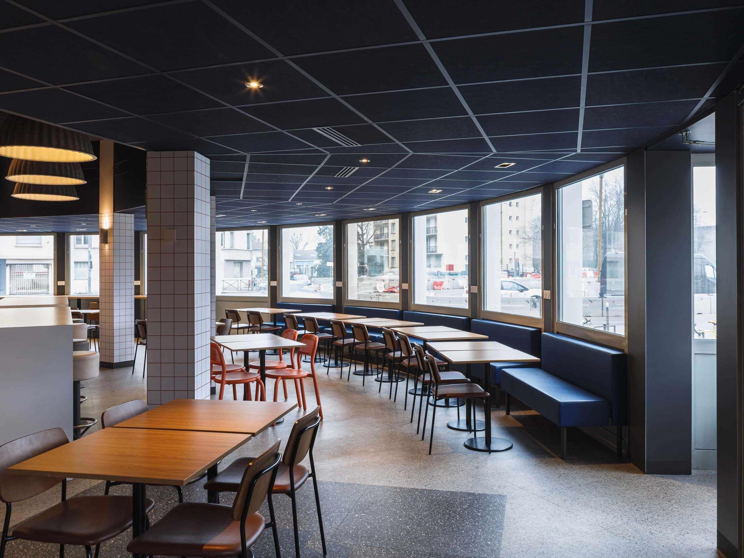 A modern cafe with large windows, wooden tables, and chairs.