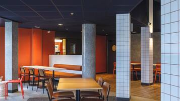 Un intérieur moderne avec un espace salon central, de hauts plafonds et une variété d’agencements de sièges.