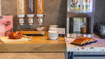 Un bar à petit-déjeuner équipé de machines à café, d’un appareil à gaufres et de bols.