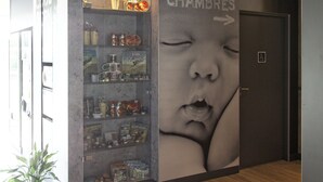 A modern interior with a wall-mounted display of various items, a wooden floor, and a door labeled "CHAMBRES". - ibis budget Cherbourg La Glacerie (Cherbourg-en-Cotentin)