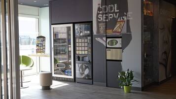 Un interior moderno con una máquina expendedora, una vitrina de vidrio y una planta en maceta.
