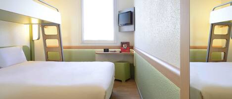Habitación de hotel con dos camas, un escritorio pequeño, un televisor y una ventana.