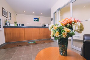 A reception area with a wooden counter, a logo on the wall, and a floral arrangement on a table.