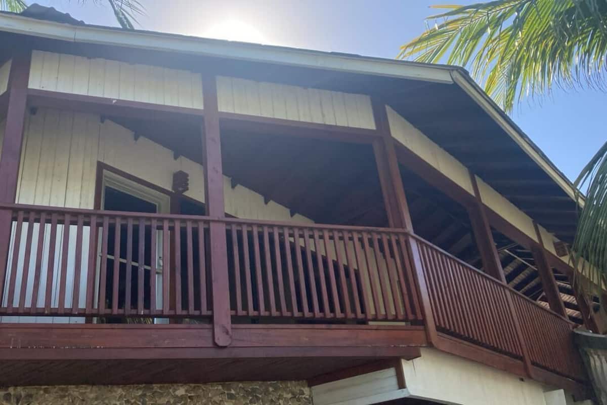 A two-story building with a balcony and a stone foundation.