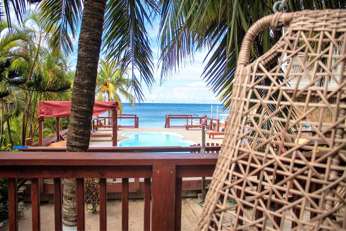 A beachside area with a pool, wooden deck, and lounge chairs.