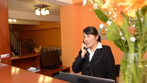 Un mostrador de recepción con una computadora, un teléfono y una planta al frente.