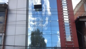 Un edificio con fachada de vidrio reflectante, un letrero que dice 'Giorgio's Pizzas' y un cartel que anuncia 'Karaoke'.