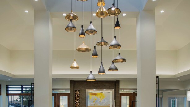Un hall d’entrée spacieux, doté de meubles modernes, d’une cheminée et de plusieurs luminaires suspendus.