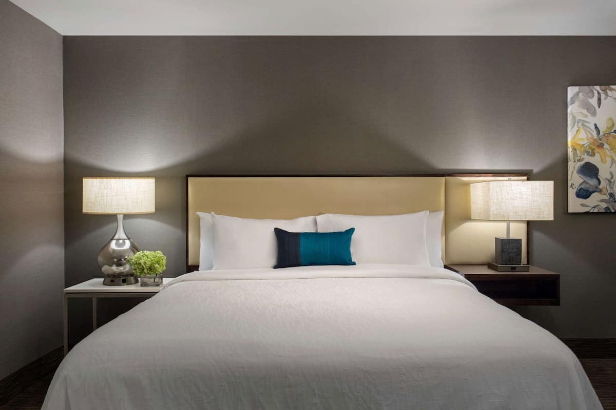 Quarto de hotel com uma cama grande, duas mesas de cabeceira e luminárias.