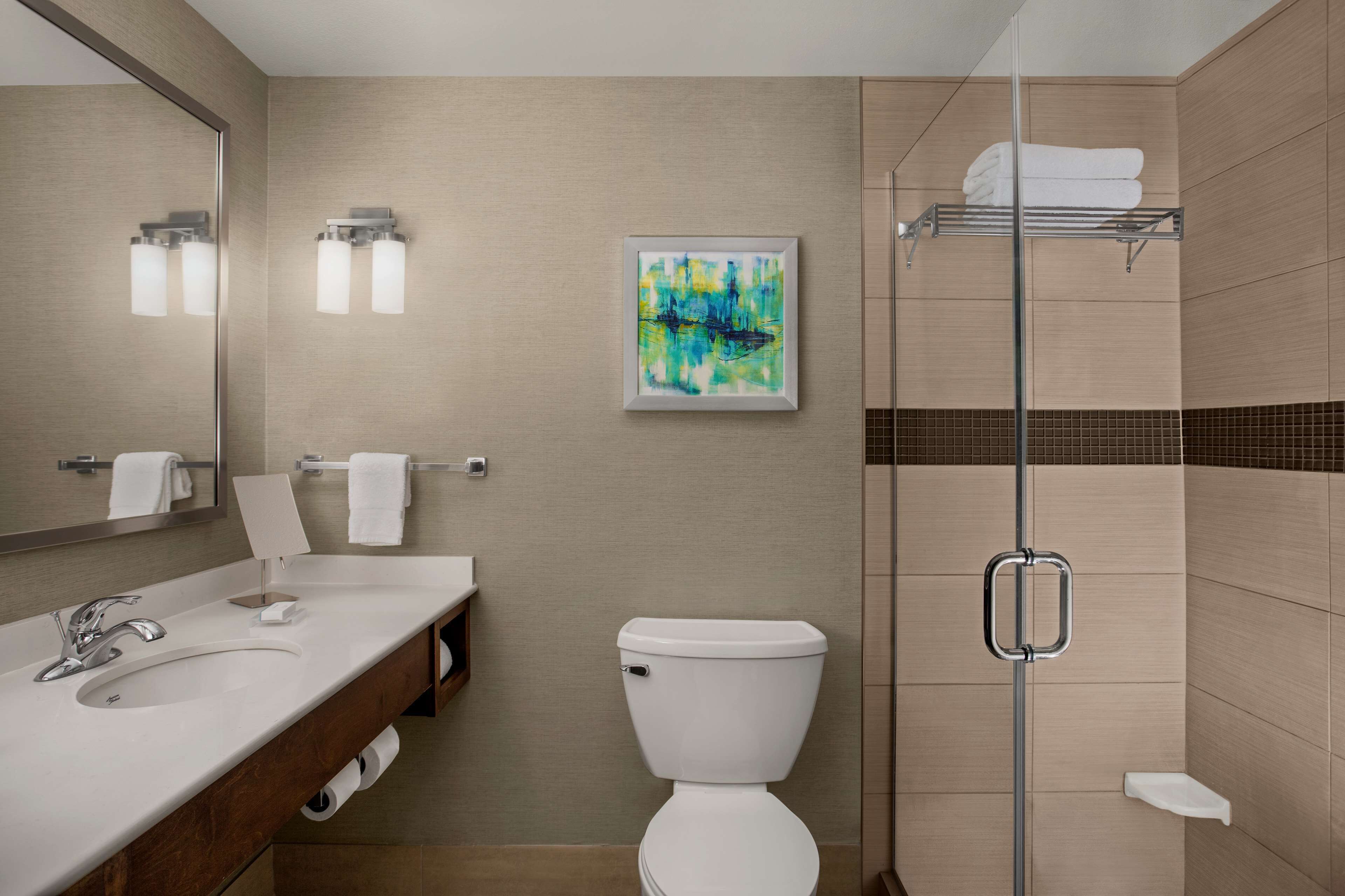 Un bagno moderno con lavandino, WC e box doccia in vetro.