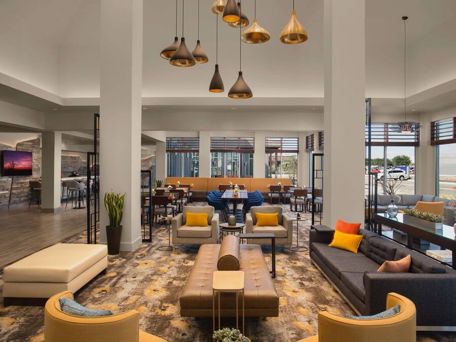 Eine geräumige Lobby mit einer Sitzecke, einer Bar und großen Fenstern mit Blick ins Freie.