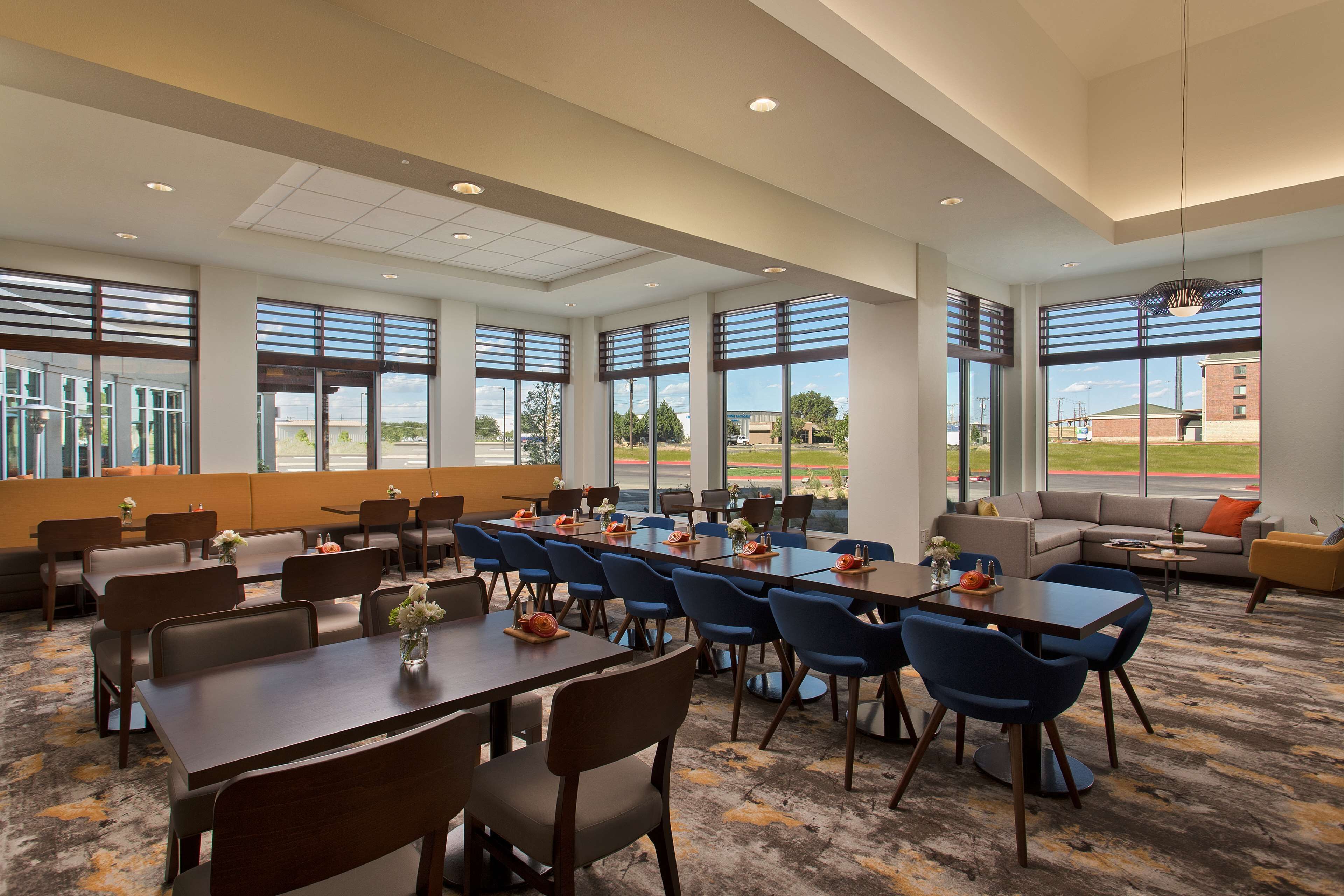 A spacious conference room with large windows, multiple tables, and chairs arranged for meetings.