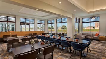 A spacious conference room with large windows, multiple tables, and chairs arranged for meetings.