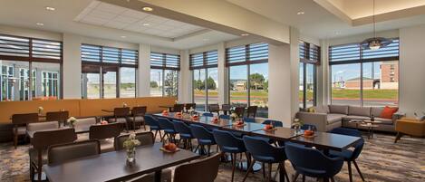 A spacious conference room with large windows, multiple tables, and chairs arranged for meetings.