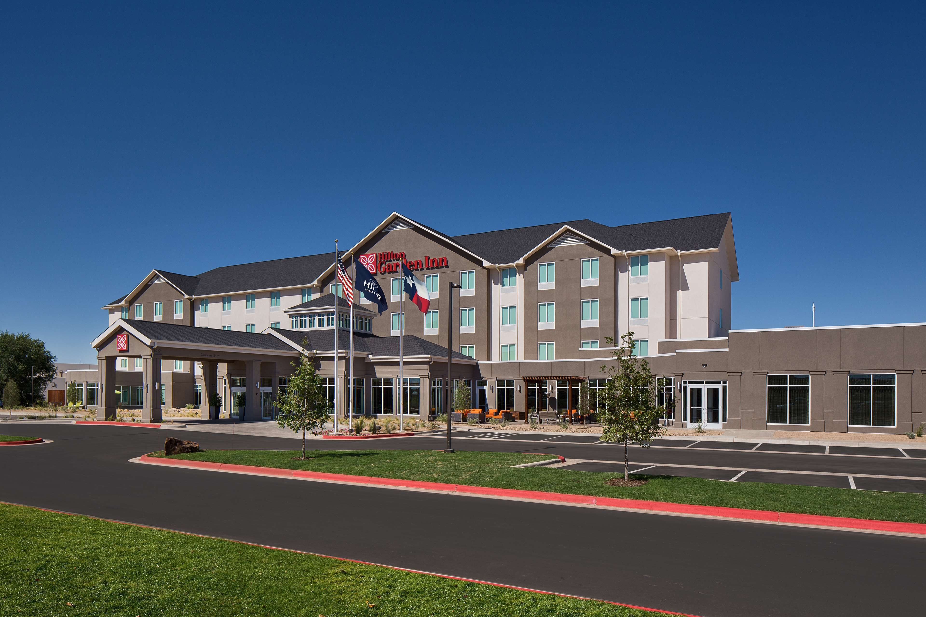 A modern hotel with a large entrance, multiple floors, and a flag.
