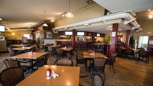 Un restaurante con varias mesas y sillas, una zona de bar y equipo de cocina.