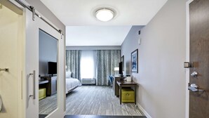 A hotel room with a bed, a desk, a chair, a television, and a window with curtains. - Hampton Inn Blue Ash/Cincinnati (Cincinnati)